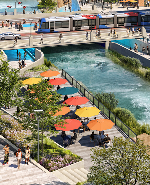 People sit under colorful umbrellas by a riverside cafe near North Temple Jordan River, as a tram crosses a bridge and pedestrians stroll the waterfront in an urban setting.