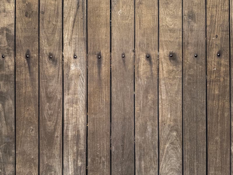 Primer plano de una cerca de madera con tablones verticales, mostrando vetas de madera natural y clavos en cada tabla, típicos del estilo clásico que se encuentra en las comunidades de Utah listas para la construcción.