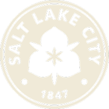 A beige circular emblem with "Salt Lake City" and "1847" text surrounds a stylized flower, reflecting the spirit of the Salt Lake westside business district near North Temple Jordan River.