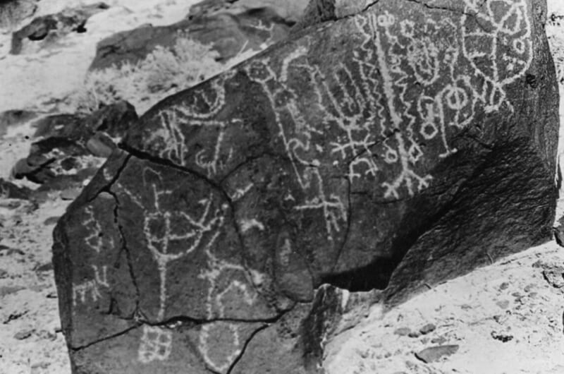 Una gran superficie rocosa con petroglifos antiguos, con figuras abstractas y geométricas, tallados en la piedra oscura cerca del desarrollo listo para iniciar en Utah, por el que es conocido, en un paisaje desértico impactante.