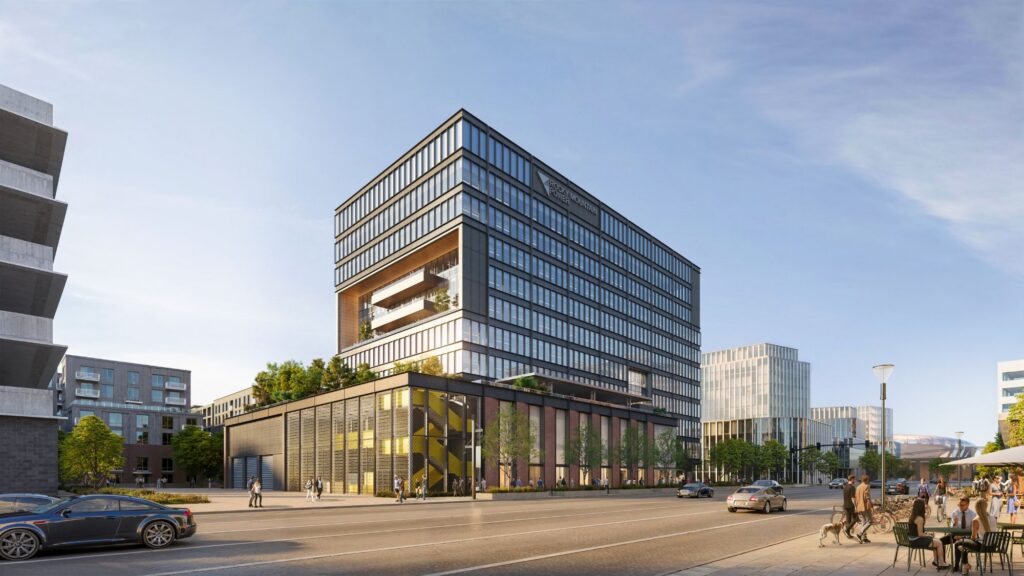 Edificio de oficinas moderno con grandes ventanales y una terraza al aire libre, ubicado en el vibrante distrito de negocios del oeste de Salt Lake, rodeado de calles urbanas con autos, peatones y asientos al aire libre.