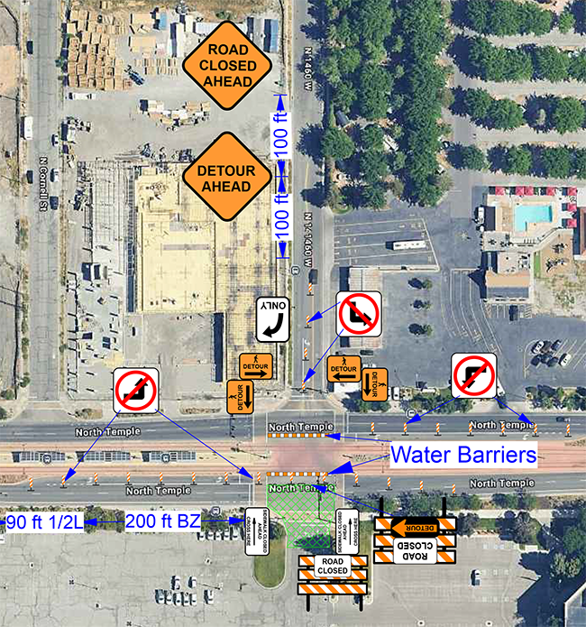 Aerial view of a road closure with detour and road closed signs, water barriers, and directional arrows along North Temple and 300 West streets. Construction site visible to the northwest.